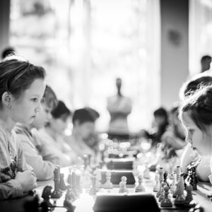 grayscale photography of children sitting while playing chess